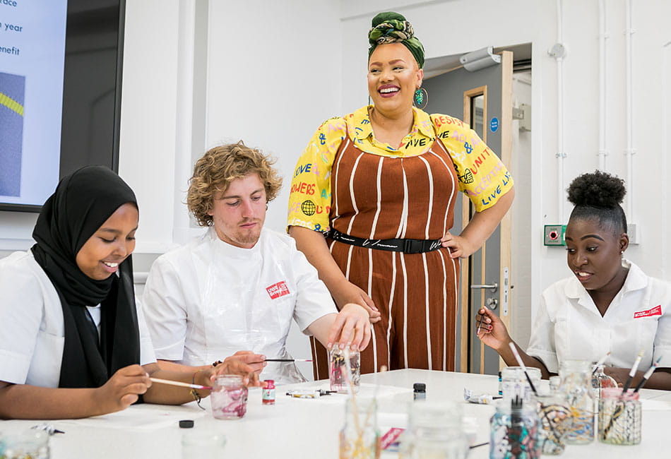 A group of people painting glass jars.