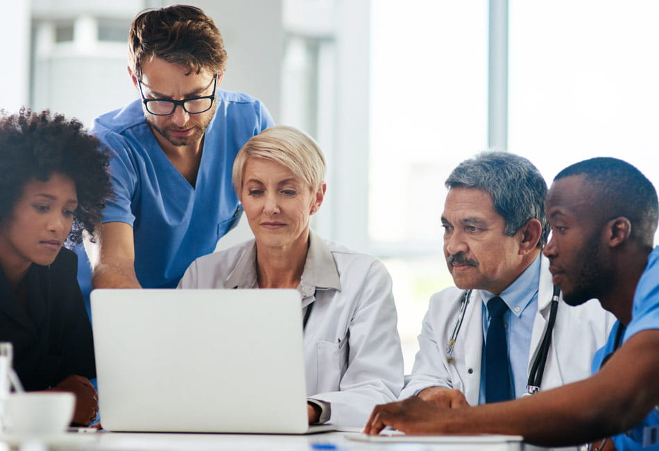 Healthcare professionals gathered around a laptop having a discussion