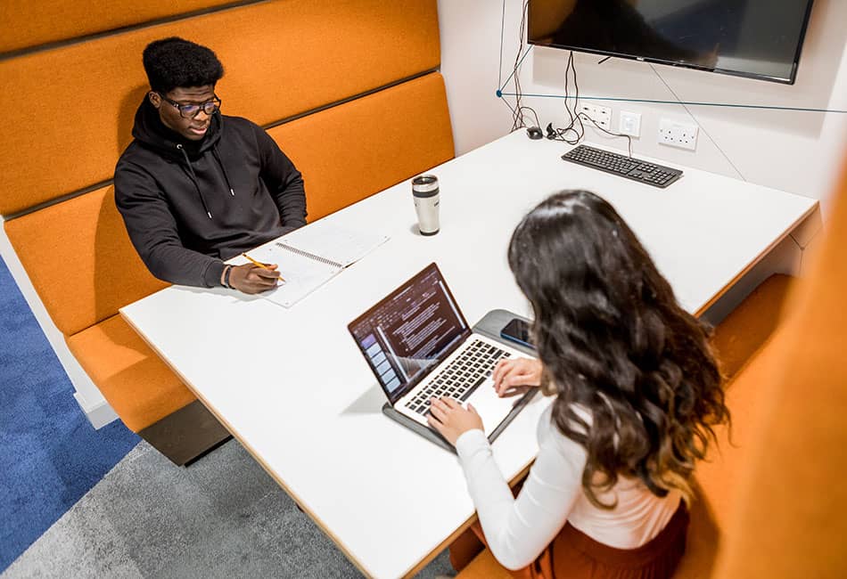 Two students studying in a booth.