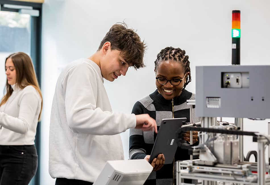 Two students working together at a piece of technical equipment.