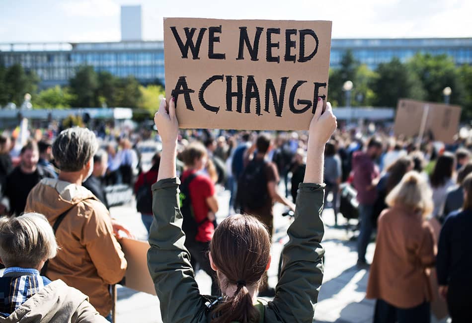 A crowd of protestors with slogan 'We need a change'.