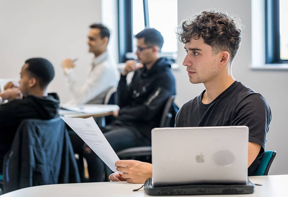 A group of students in a classroom facing forwards, possibly watching a presentation.