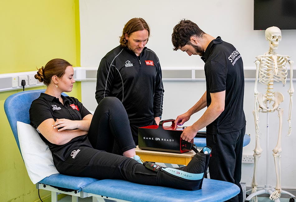 A student massaging a patient under the guidance of a lecturer.