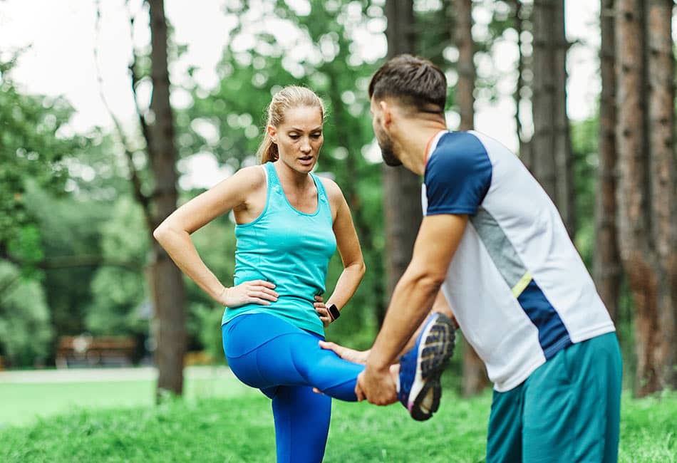 Jogger having her leg support up by a sports therapist.